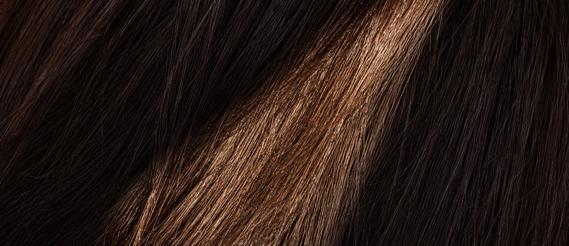Cortina de cabelo escuro preenchendo o quadro, com uma faixa de luz atravessando na diagonal.